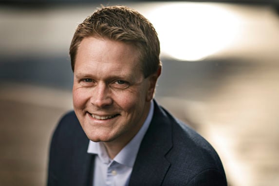 Portrait of a smiling Harald Solberg against a brown backdrop 