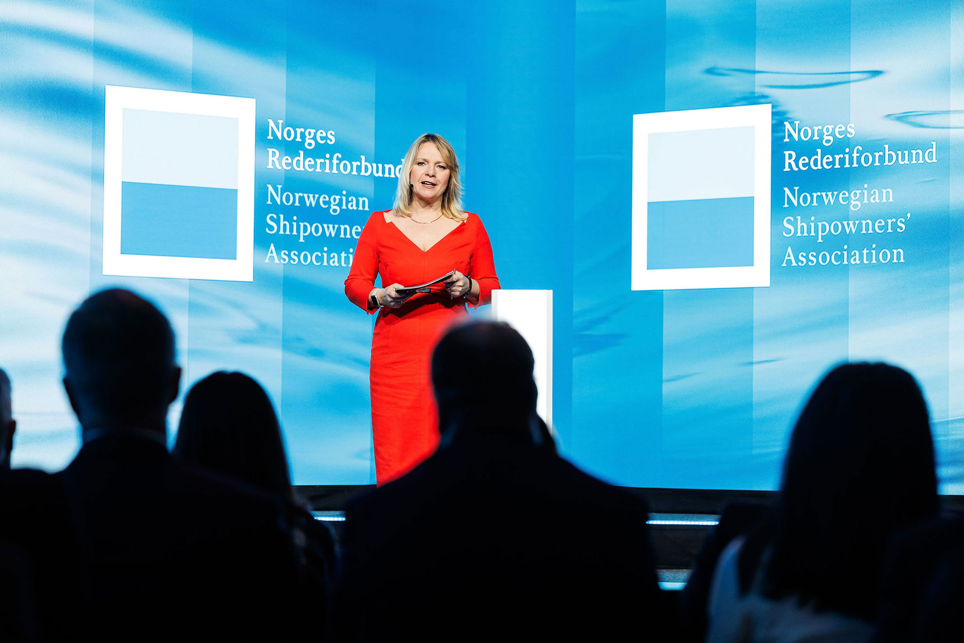moderator susannah streeter på scenen under årskonferansen 2024 iført rød-oransje kjole