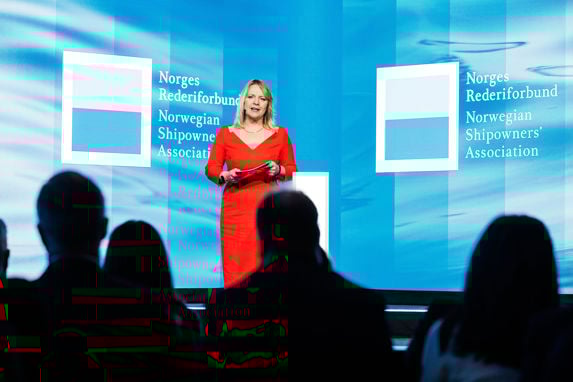 moderator susannah streeter på scenen under årskonferansen 2024 iført rød-oransje kjole