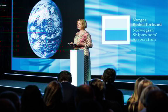 Forfatter Erika Fatland på scenen under årskonferasnen 2024 med en jordklode og rederiforbundets logo i bakgrunnen
