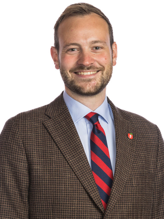 portrait of sivert bjørnstad from the progress party, wearing a brown blazer and a red and balck striped tie