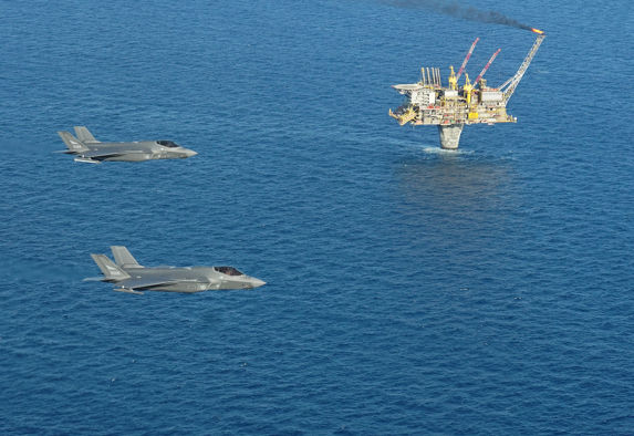 alt="To F-35 jagerfly flyr over en oljeplattform "