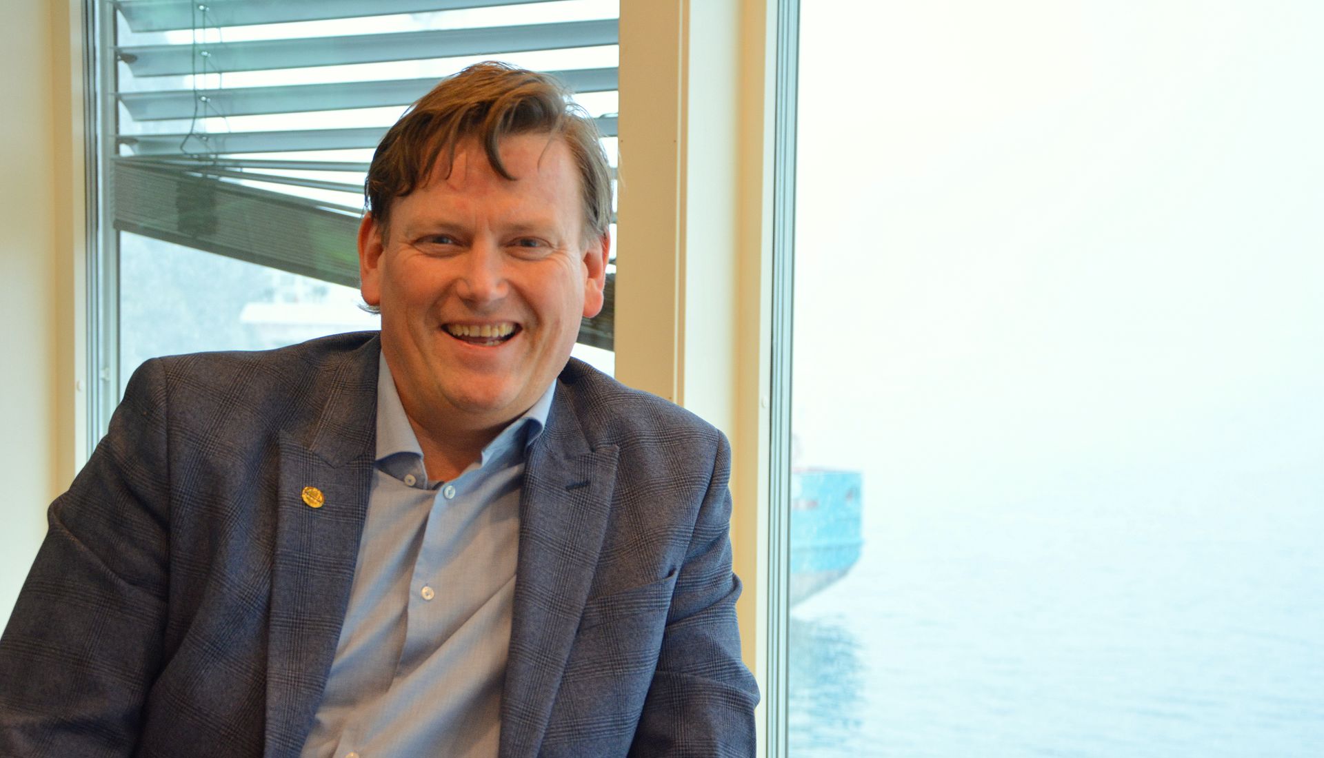 Kjell Olav Haugland smiler foran vinduet på kontoret