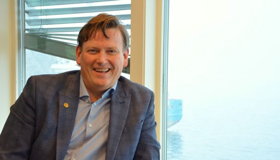 Kjell Olav Haugland smiler foran vinduet på kontoret