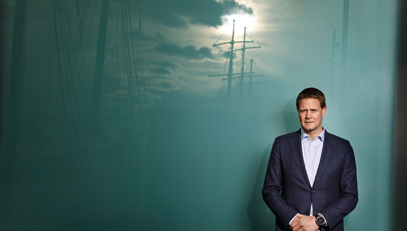Harald Solberg foran en blå bakgrunn som reflekterer et skip 
