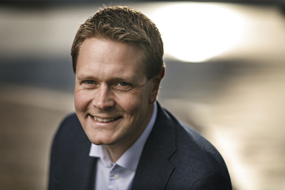 Portrait of a smiling Harald Solberg against a brown backdrop 