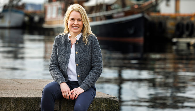 portrett av Karin Gjerløw Høidahl utendørs med en båt i bakgrunnen, 