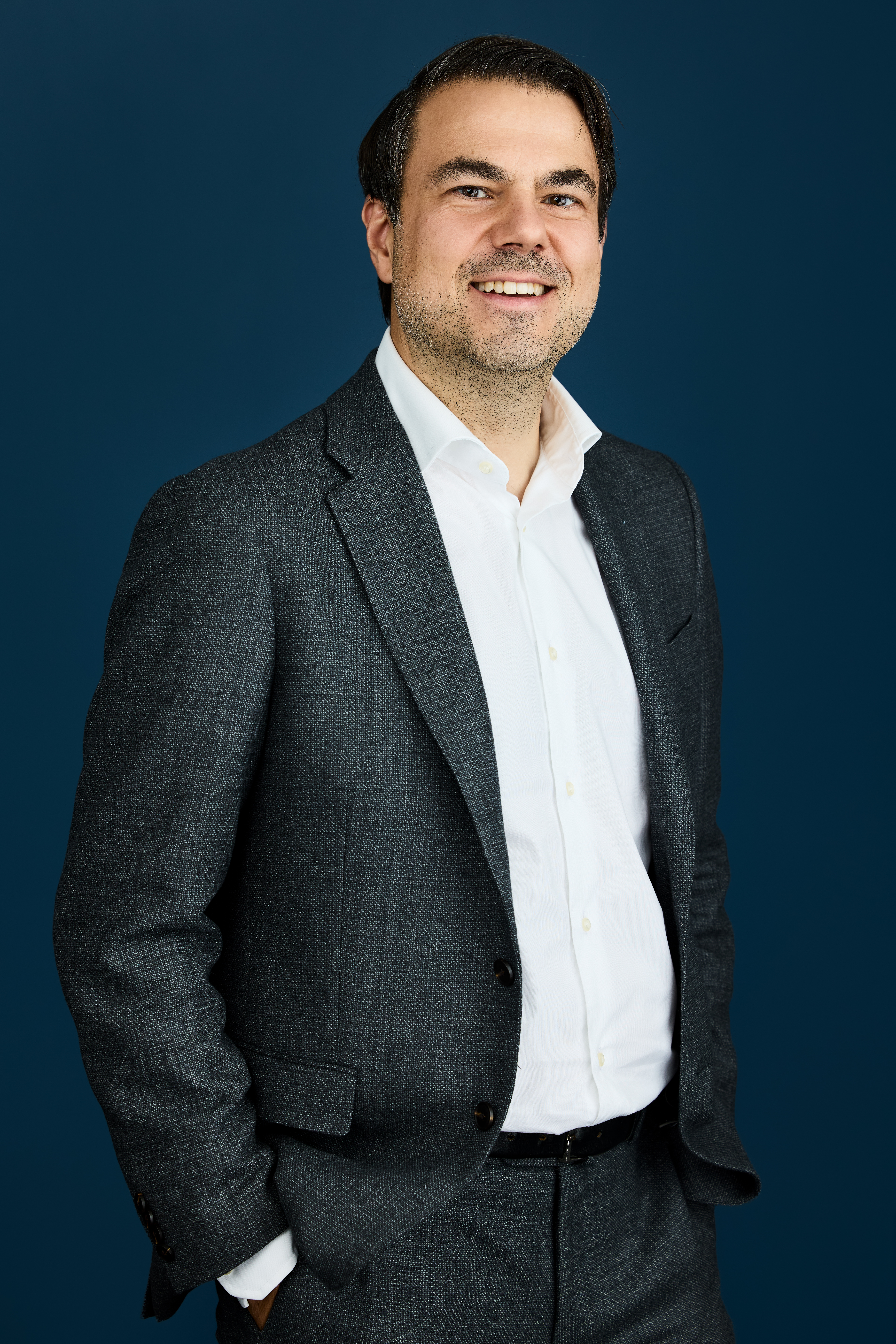 Portrett av Tom Johnsen mot mørkblå bakgrunn 