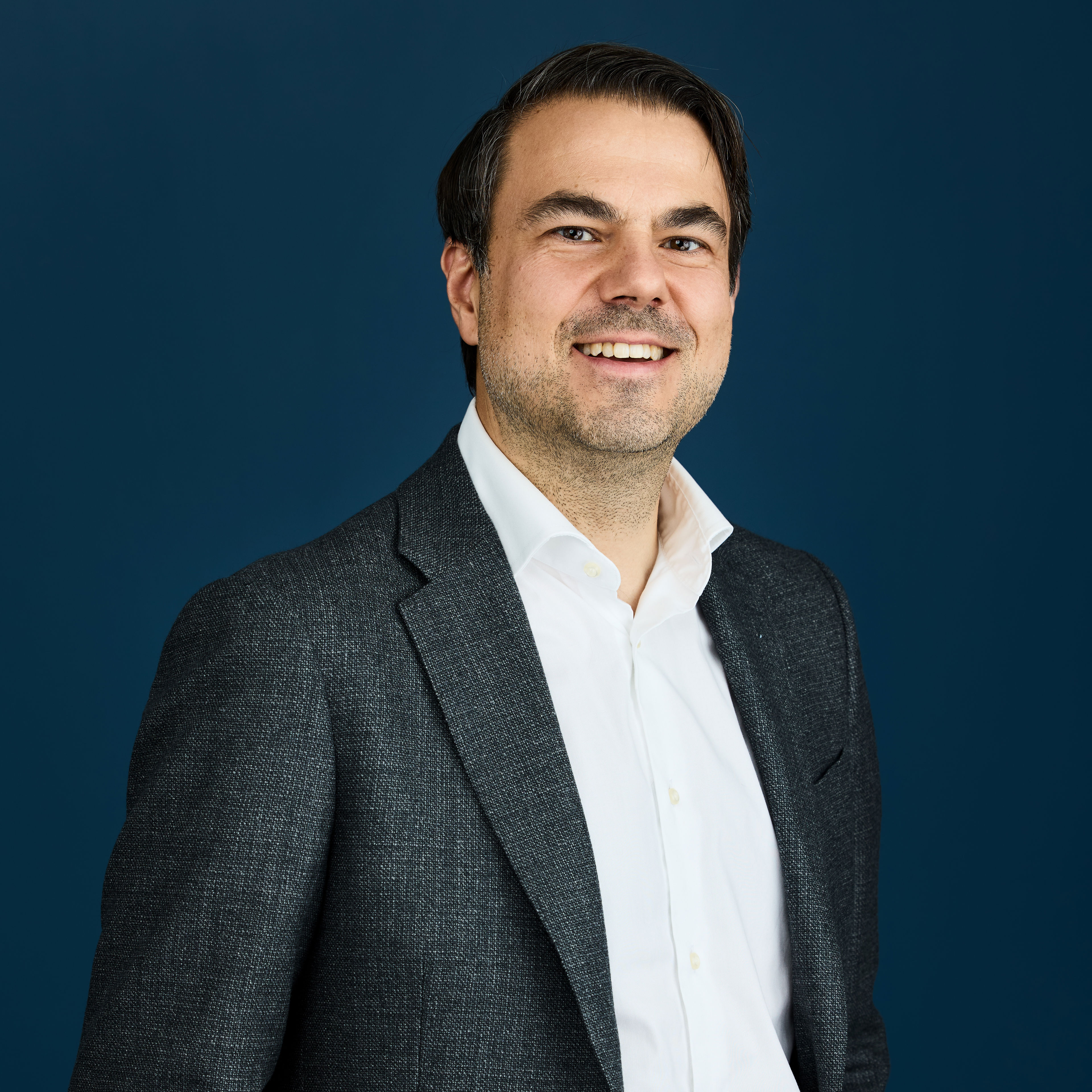 Portrett av Tom Johnsen mot mørkblå bakgrunn