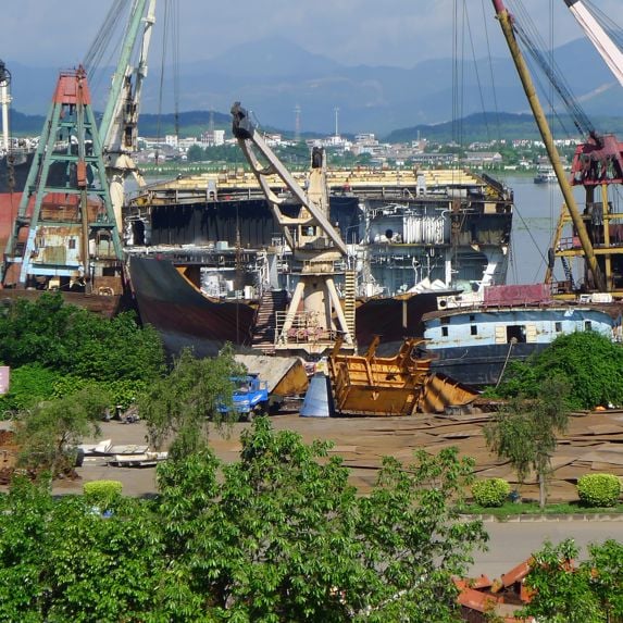 alt="Photo from a ship recycling yard - a blue ship being dismantled "