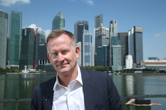 Laurence Odfjell i dress foran Singapores skyline av skyskrapere