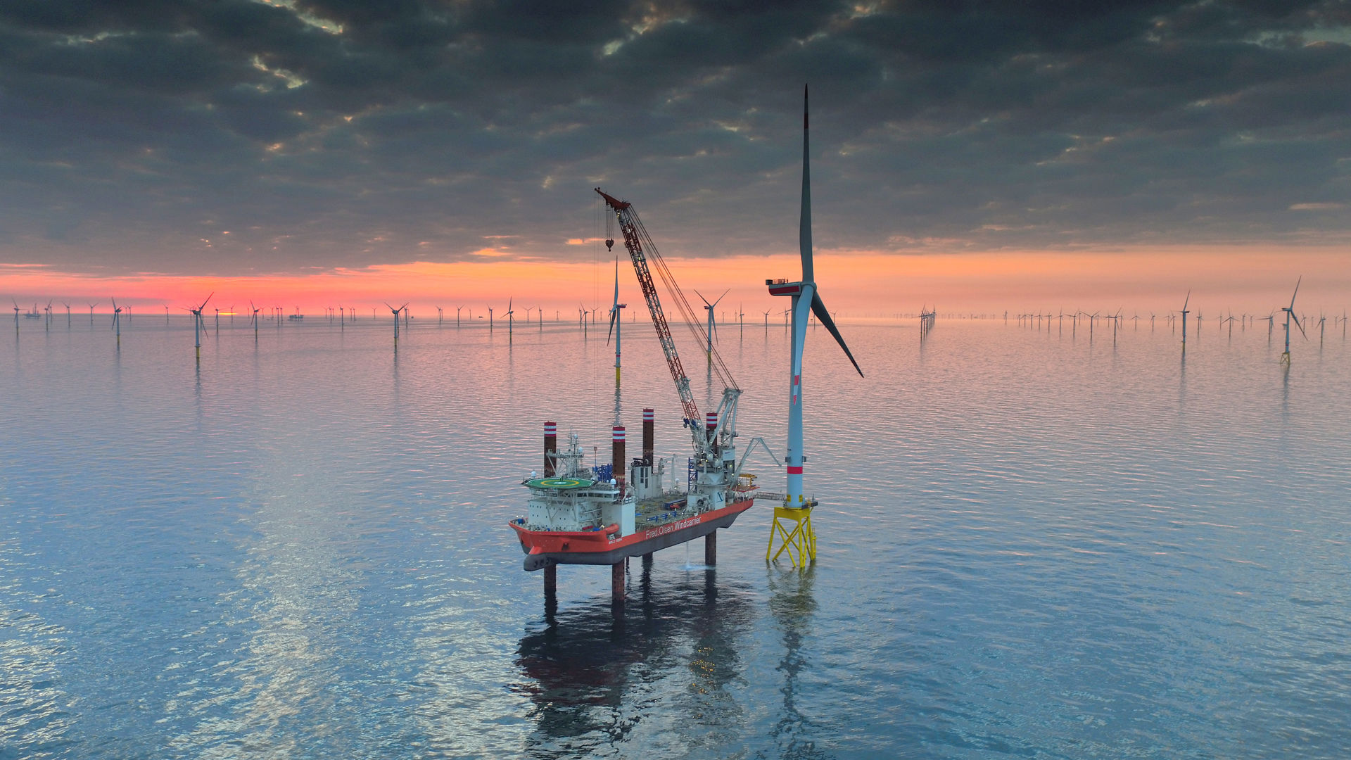 Oppjekkbart skip fra Fred. Olsen Windcarrier i arbeid på vindpark i solnedgang.