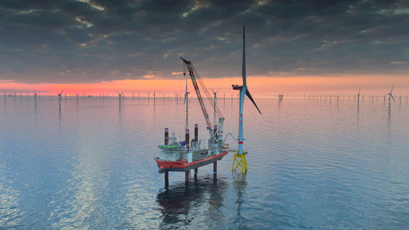 Oppjekkbart skip fra Fred. Olsen Windcarrier i arbeid på vindpark i solnedgang. 