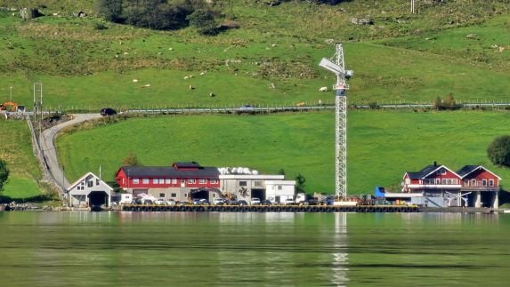 Langs fjorden ligger Arriva Shippings lokaler i Ølensvåg. I bakgrunnen er store, grønne sauebeiter. 