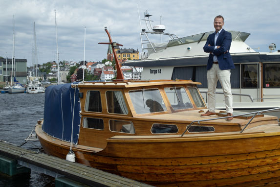 Rolf Thore Roppestad i beige chinos og blå jakke, stående på dekket til snekka oldefaren hans har bygget