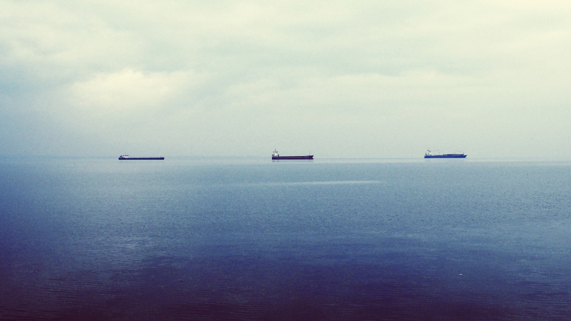 Two ships on the horizon. Blue sea and grey skies. 