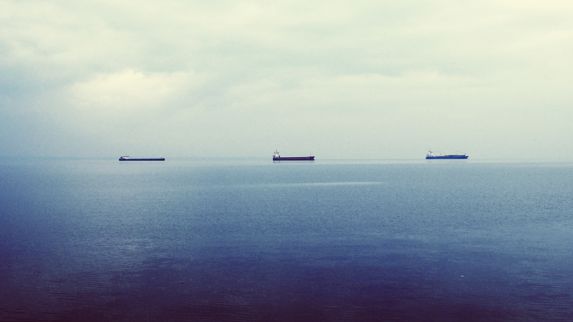 Two ships on the horizon. Blue sea and grey skies.
