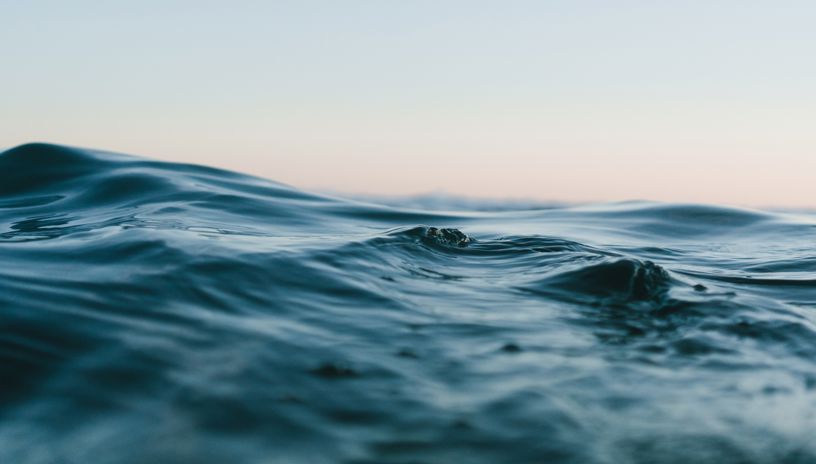 Blue wave seen up close, lighter blue sky 